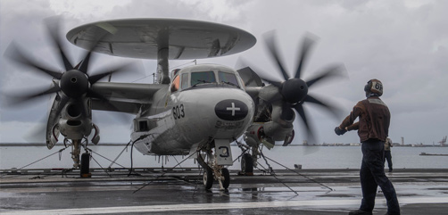 Navy Seaman Mathieu Carroll signals an E-2C Hawkeye to power up its propellers on the flight deck of the USS Theodore Roosevelt, May 11, 2020. - ALLOW IMAGES